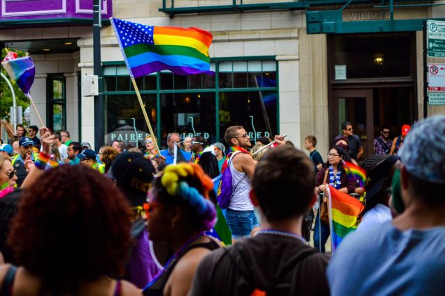 People Gathered Near Building Holding a Pride Flag at a Parade